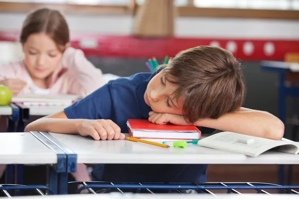 Chłopiec śpi a dziewczyna studiuje w tle — Zdjęcie stockowe