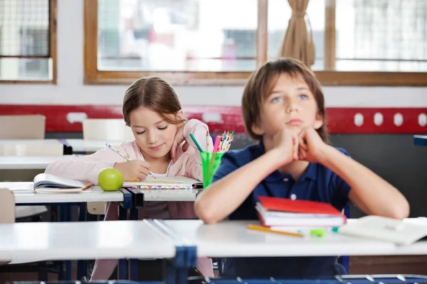 Schoolmeisje schrijven aantekeningen in klas — Stockfoto