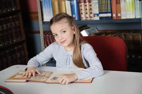 Kleines Mädchen sitzt mit Büchern am Tisch — Stockfoto
