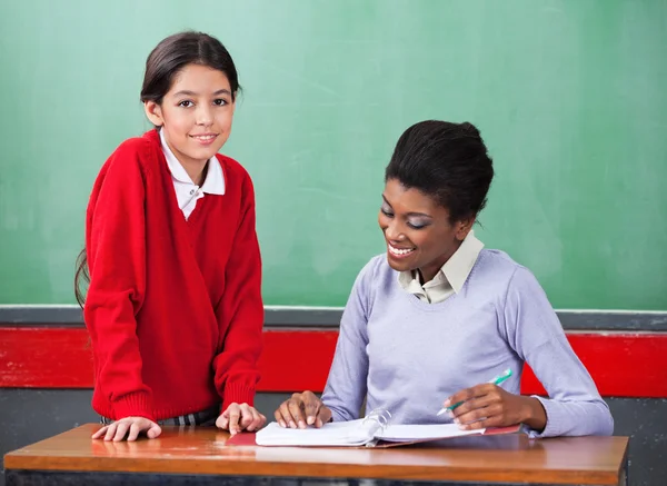 Schulmädchen mit Lehrer-Leseheft am Schreibtisch — Stockfoto