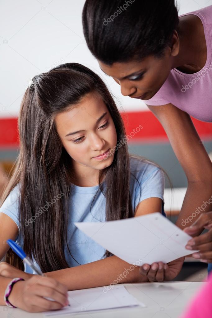 Teacher Assisting Teenage Schoolgirl During Examination