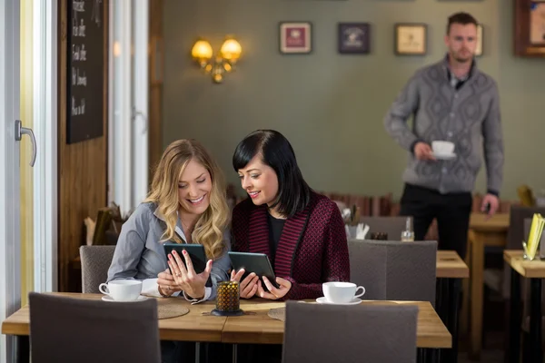 Amigos femininos usando comprimidos digitais no café — Fotografia de Stock