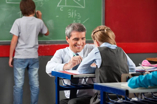 Profesor ayudando a la colegiala en el escritorio —  Fotos de Stock