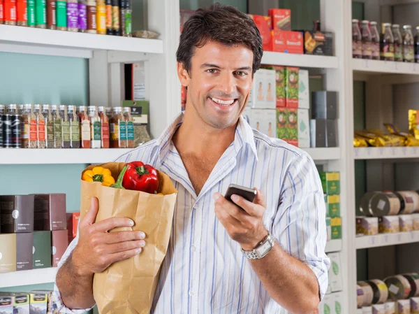 Man met mobiele telefoon en kruidenier papieren zak — Stockfoto