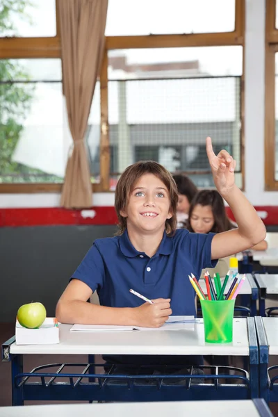 Glücklicher Schüler hebt die Hand im Klassenzimmer — Stockfoto