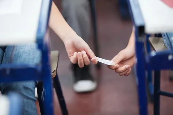 Ragazza dando cheat foglio a ragazzo durante esame — Foto Stock