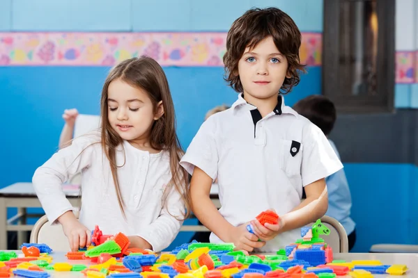 Menino com fêmea amigo jogar blocos no sala de aula — Fotografia de Stock