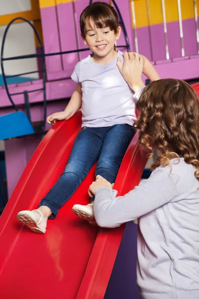 Вчитель допомагає дівчині під час гри на слайді — стокове фото