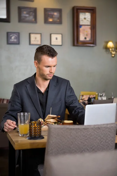 Affärsman med laptop samtidigt ha smörgås — Stockfoto