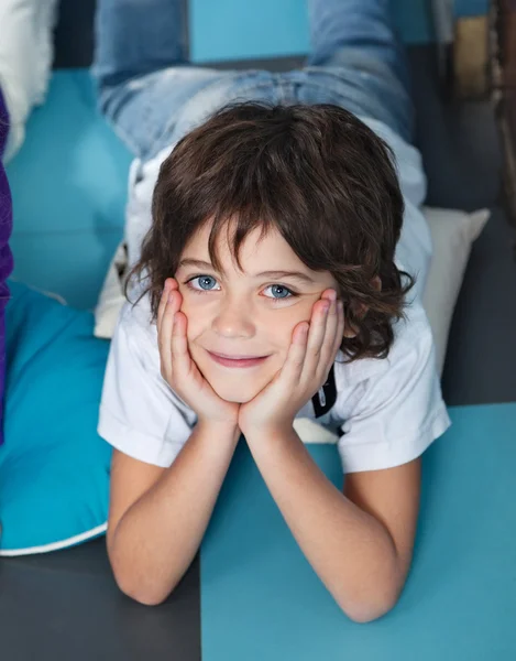 Chlapec s hlavou v rukách leží na podlaze v mateřské školce — Stock fotografie