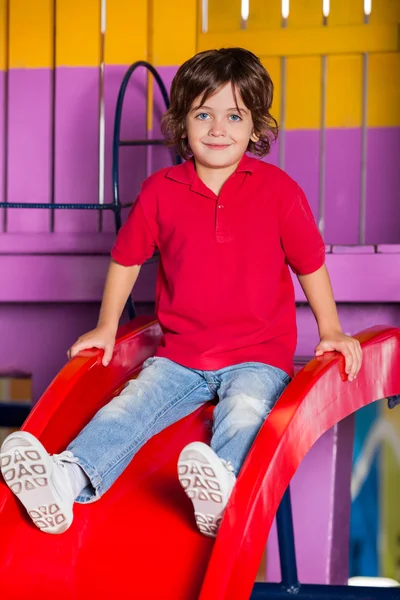 Niño jugando en la diapositiva en el jardín de infantes — Foto de Stock