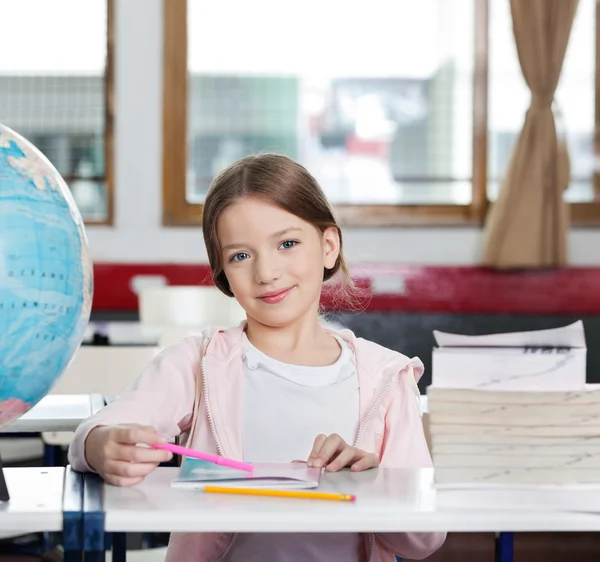 Linda chica sonriendo con libros y globo en el escritorio — Foto de Stock