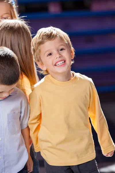 Garçon regardant loin avec des amis à la maternelle — Photo