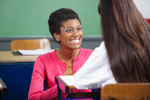 Lehrer schaut Teenager-Schülerin am Schreibtisch an — Stockfoto