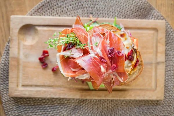 Delicioso emparedado de jamón de Parma en placa de madera — Foto de Stock