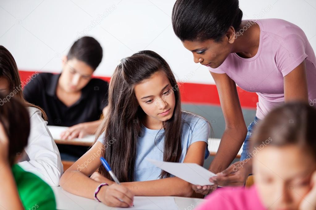 Teacher Assisting To Teenage Girl During Examination