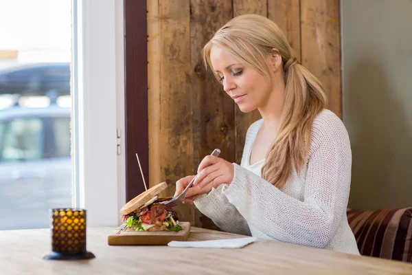 Młoda kobieta jedzenie hamburgera w restauracji — Zdjęcie stockowe