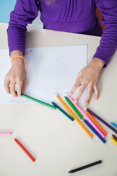 Девушка с цветными карандашами и бумагой за столом — стоковое фото