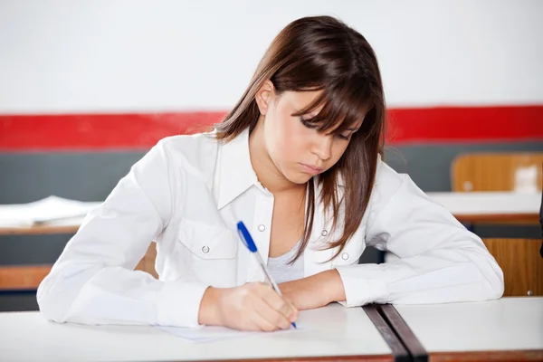 Teenage schoolmeisje schrijven tijdens onderzoek — Stockfoto