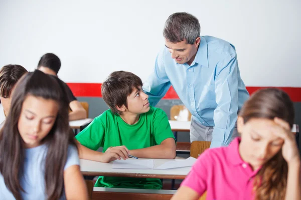 Schooljongen en leraar kijken elkaar tijdens onderzoek — Stockfoto