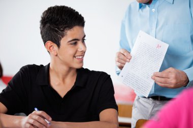 Masa başında kağıt ile genç çocuk tutan Profesör