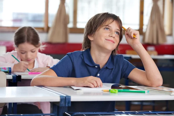 Kleiner Junge lächelt, während er im Klassenzimmer nach oben schaut — Stockfoto