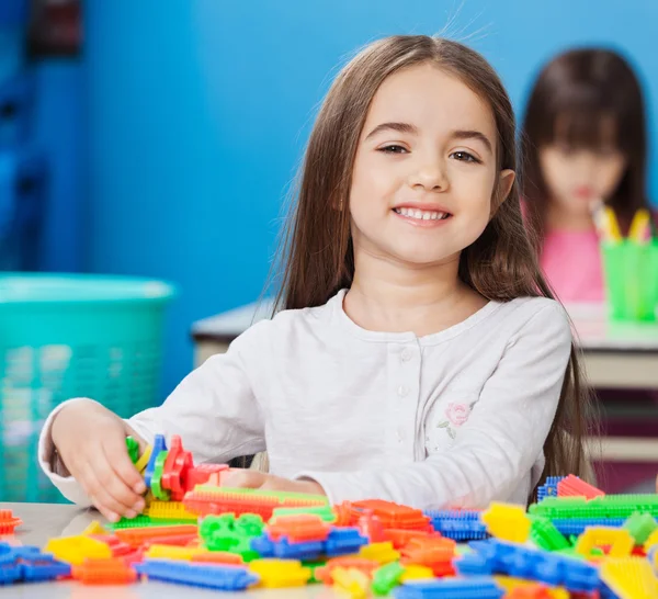 Girl Playing With Construction Blocks With Friends In Background — Stock Photo, Image