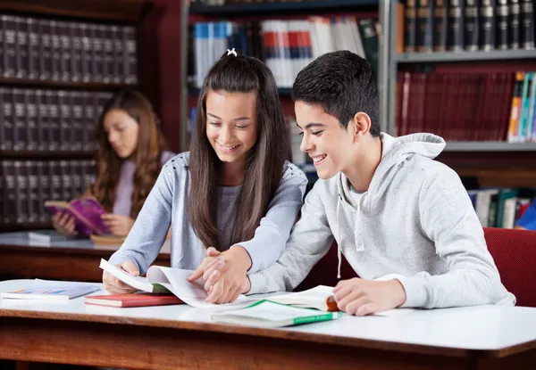 Pareja adolescente estudiando juntos en la biblioteca —  Fotos de Stock