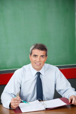 cildi ve kalem masa başında oturan Profesör