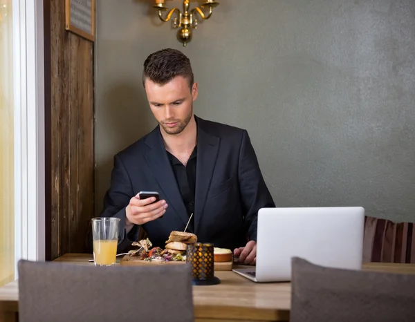 Businessman Messaging On Mobilephone While Having Meal In Cafe — Stock Photo, Image