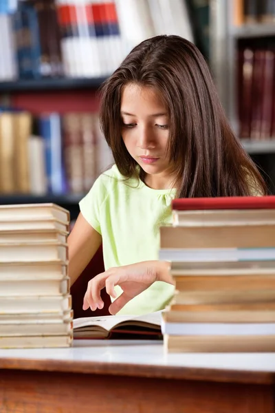 Colegiala lectura libro con pila de libros en la mesa —  Fotos de Stock