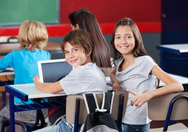 Школьники с цифровыми планшетами сидят в классе — стоковое фото