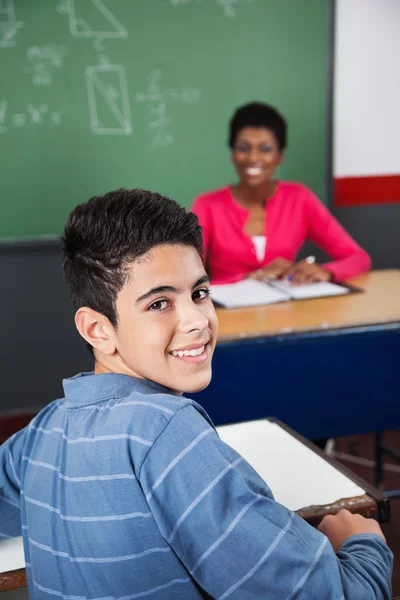 Feliz adolescente colegial sentado en el escritorio — Foto de Stock