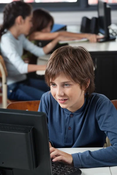 Écolier utilisant l'ordinateur au bureau — Photo