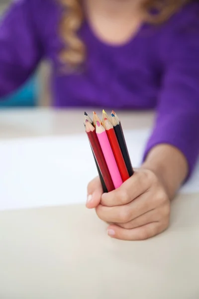 Menina segurando de lápis coloridos na sala de aula — Fotografia de Stock