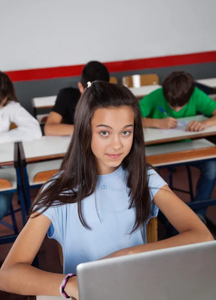 Docela dospívající školačka sedí s notebookem v učebně — Stock fotografie