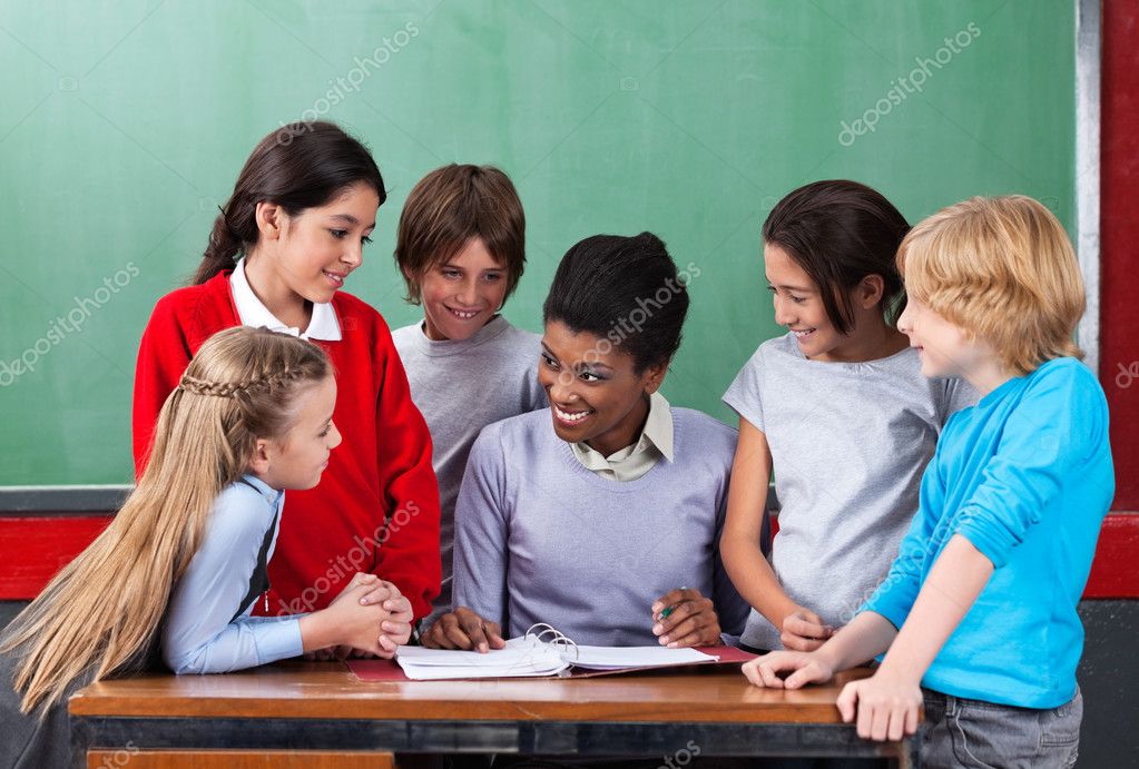 feliz professor ensinando alunos na mesa na sala de aula — Stock Photo