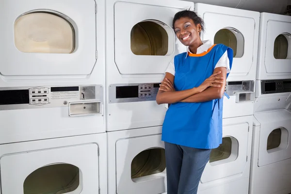 Ayudante femenina apoyada en secadoras en lavandería —  Fotos de Stock