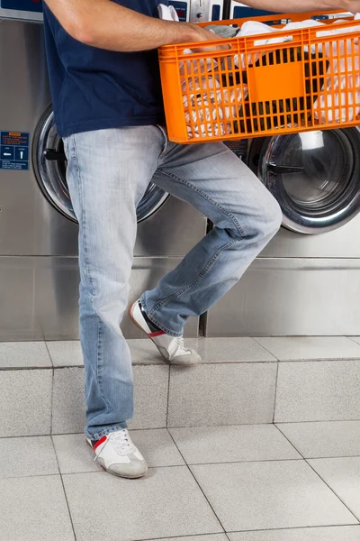 Homem segurando cesta de roupas na lavanderia — Fotografia de Stock