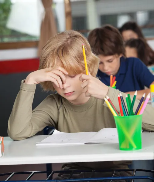 Скучный школьник сидит за столом в классе — стоковое фото