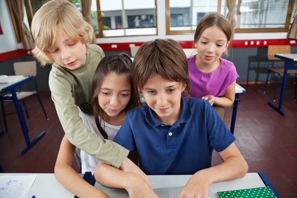 Söt skolbarn använder laptop på skrivbordet — Stockfoto