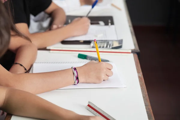 Midsection das crianças da escola que escrevem na mesa — Fotografia de Stock