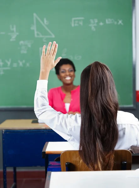 Visão traseira da aluna levantando a mão na sala de aula — Fotografia de Stock