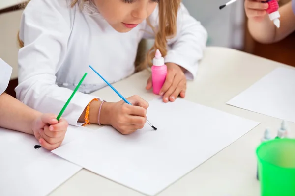 Ragazza pittura a scrivania nella scuola materna — Foto Stock