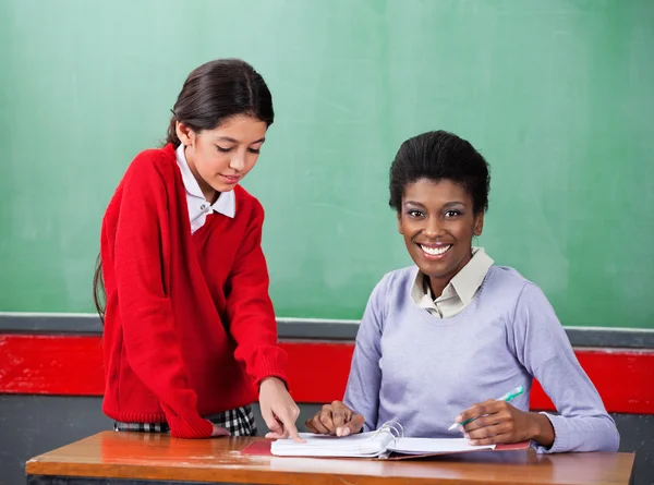 Portrét učitele s holkou ukazující na pořadače na stůl — Stock fotografie