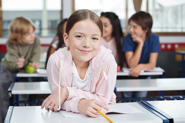 Colegiala sonriendo mientras se apoya en el escritorio — Foto de Stock