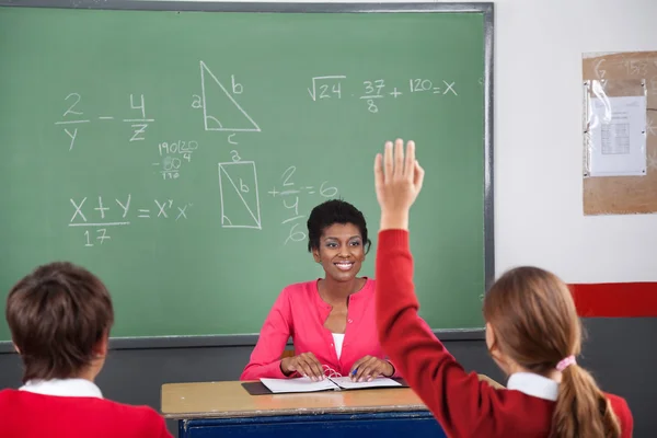 Adolescente chica levantando la mano mientras profesora mirándola —  Fotos de Stock
