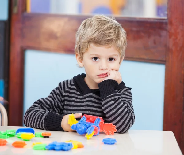 Несчастный мальчик с блоками в классе — стоковое фото