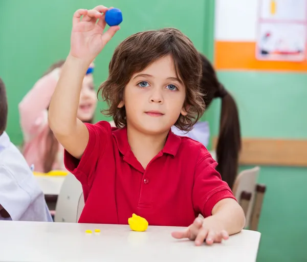Menino mostrando argila na sala de aula — Fotografia de Stock