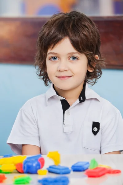 Netter Junge mit Bauklötzen auf dem Schreibtisch im Kindergarten — Stockfoto